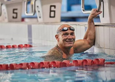 photo of michael klim in a swimming pool lane, he is wearing goggles on his head and smiling at the camera