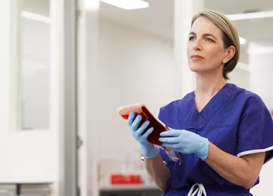 photo of nurse emma wearing a blue top and gloves holding a blood bag