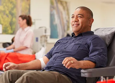 photo of a donor seated in a chair and smiling with a nurse standing in the background