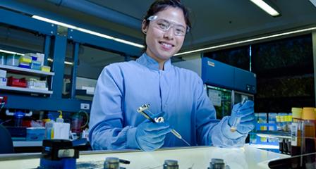 a scientist is in a laboratory wearing blue gloves and protective glasses while holding a test tube