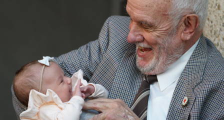 image of an elderly man holding a baby girl wearing a white bow band