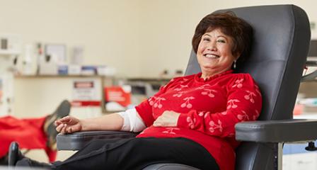 A female blood donor wearing read and smiling at the camera 