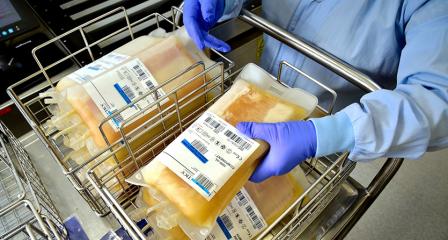 bags of plasma in a trolley with a lab worker picking one up