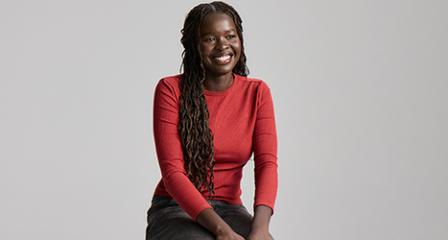 woman in red top sitting with hands on lap smiling