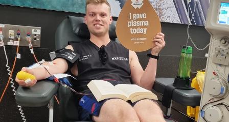 young male plasma donor holding up a sign that says i donated plasma in the donor chair