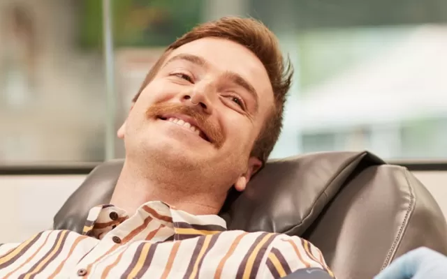 Man donating blood in a chair, smiling