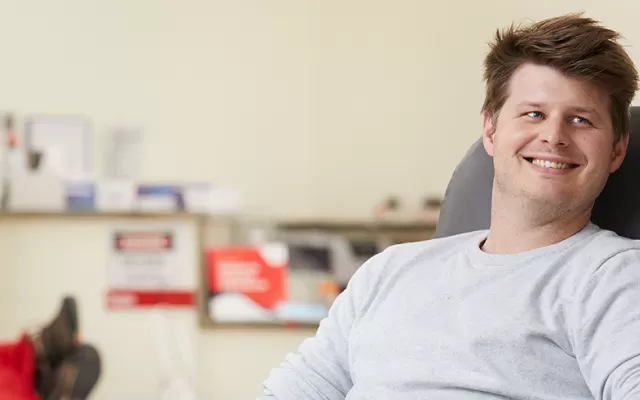 Male donor sitting in a chair, smiling