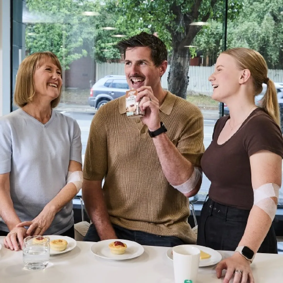 three people behind a benchtop eating snacks and drinking iced coffee