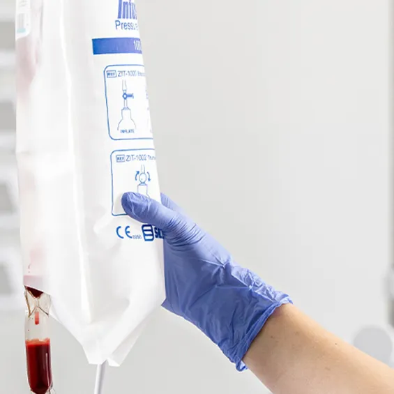 blue gloved hand holding IV bag