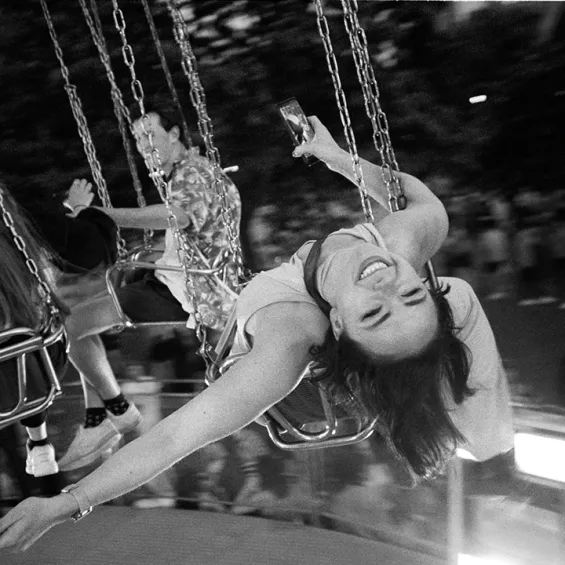 a woman on a fairground ride smiling and leaning back