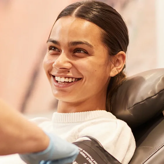 photo of a nurse standing beside a donor in a chair mid conversation and smiling at one another