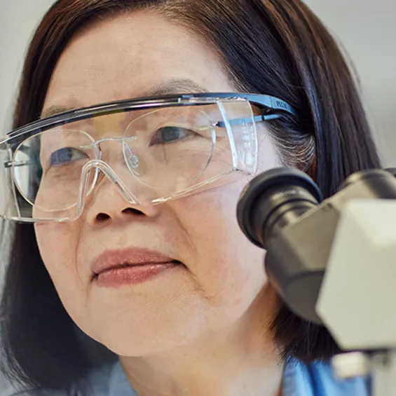 close up of a scientist wearing goggles next to a microscope