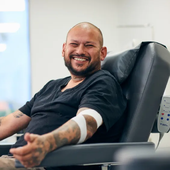 a person with tattoos with a bandage around their elbow smiling