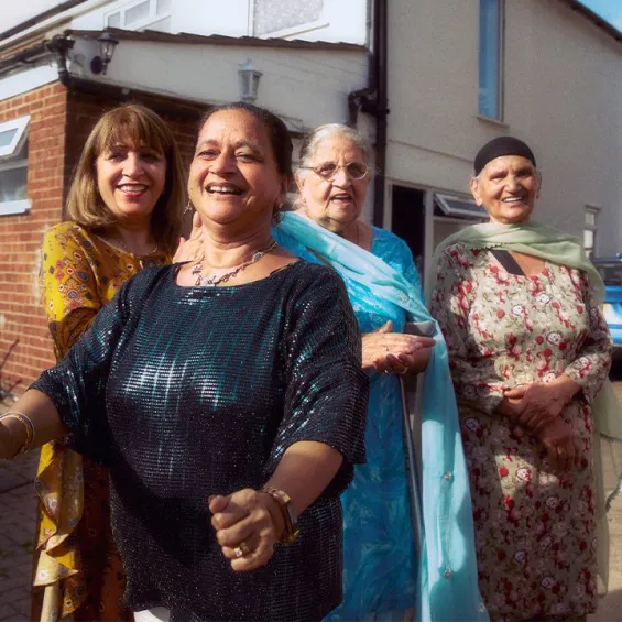 a group of people gathered outside a house laughing and smiling