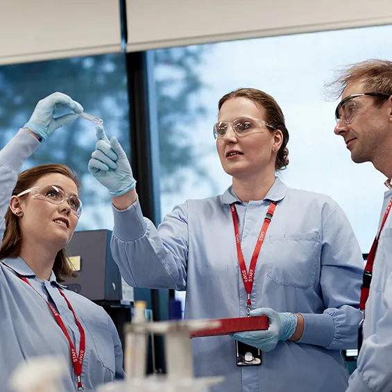 three people in lab coats and goggles talking