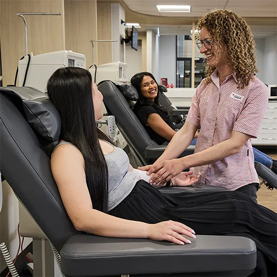 two people seated in donor chairs with a nurse talking to them