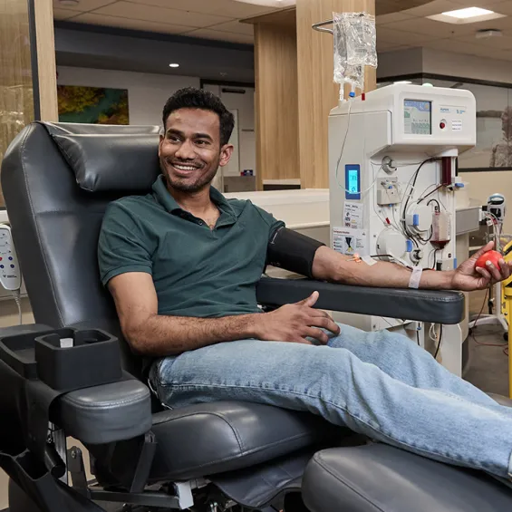 a man seated in a donor chair smiling during a donation
