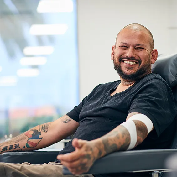 a person with tattoos with a bandage around their elbow smiling