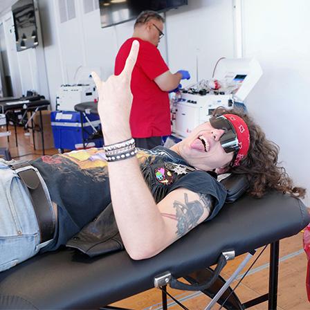 a man dressed in a band shirt giving metal horns in a donor centre