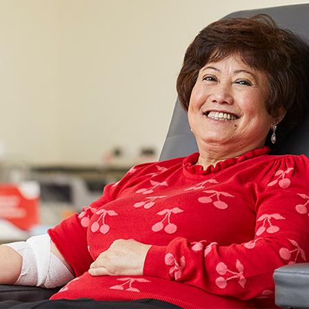 a woman seated in a donor chair smiling