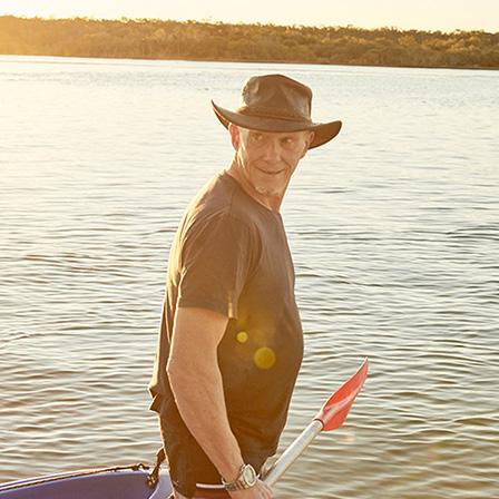 a group of men carrying kayaks into water