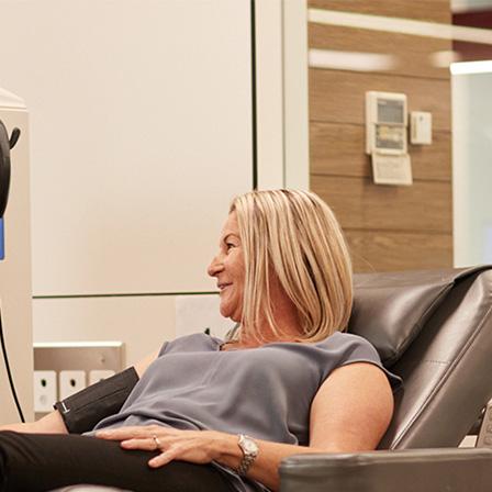 a woman sitting in a donor chair talking to a nurse
