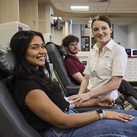 Donor sitting on chair smiling with nursing staff beside them