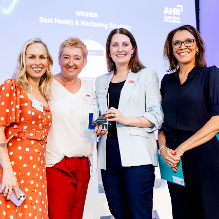 four women smiling and holding an award
