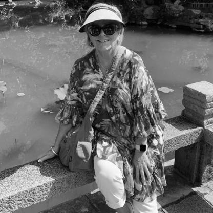 lady sitting on a wall by a pond