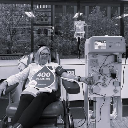 A woman donating on a couch with a 400 donation milestone card on her