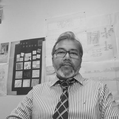 man sitting down with hands flolded in front of him, looking to camera