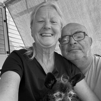 female and male smiling to camera holding a small dog