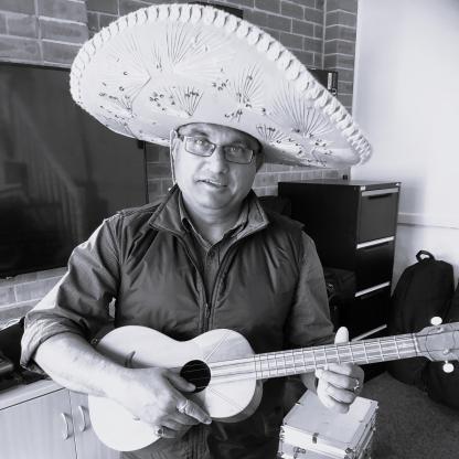 A man wearing a Latin American wide brimmed style hat and holding a guitar