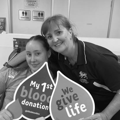 mother and daughter smiling to camera - daughter holding 'my 1st donation' sign
