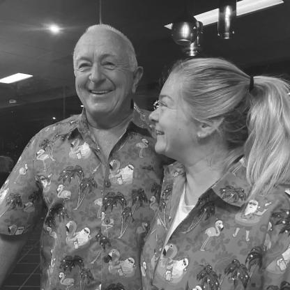 father and daughter wearing matching red hawaiian shirts with palm trees and pink flamingoes