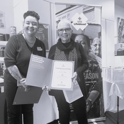 A woman holding a 200 donation milestone certificate