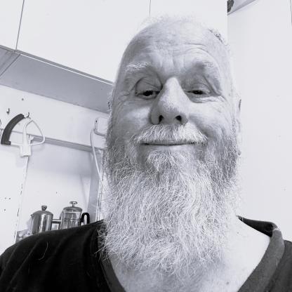 A man with a long beard smiling broadly at the camera