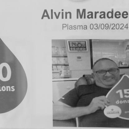 man sitting in the donor chair holding 150 donations sign