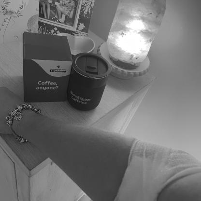 person showing their post donationbandage with a Lifeblood gifts coffee mug on a table next to them
