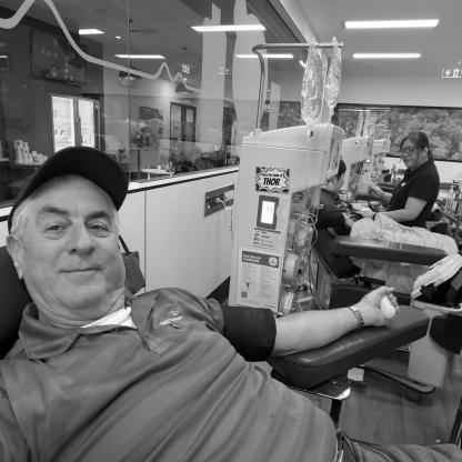 man sitting in the donor chair during his donation, taking a selfie showing the needle in his arm