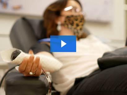 a woman is sitting in a donation chair giving a plasma donation