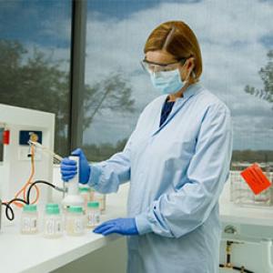 a scientist is in a laboratory wearing blue gloves and protective glasses while holding a test tube