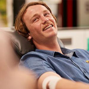 photo of a donor sitting back in a chair during a donation looking up and smiling