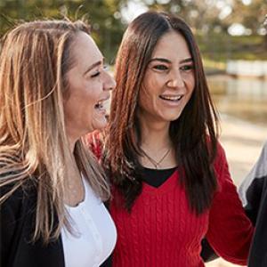 photo of two women standing outdoors having a conversation and smiling