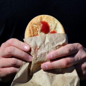 hands holding a pie with sauce
