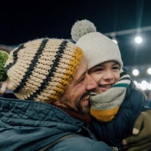 a man and child wearing knitted beanies in a stadium