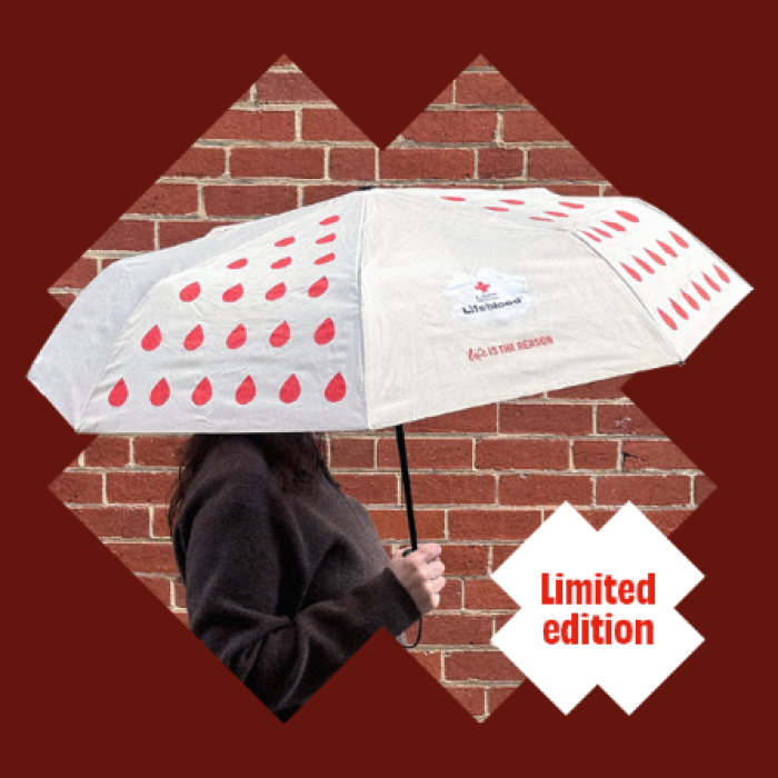 a person holding an umbrella with red droplets and the lifeblood logo on it