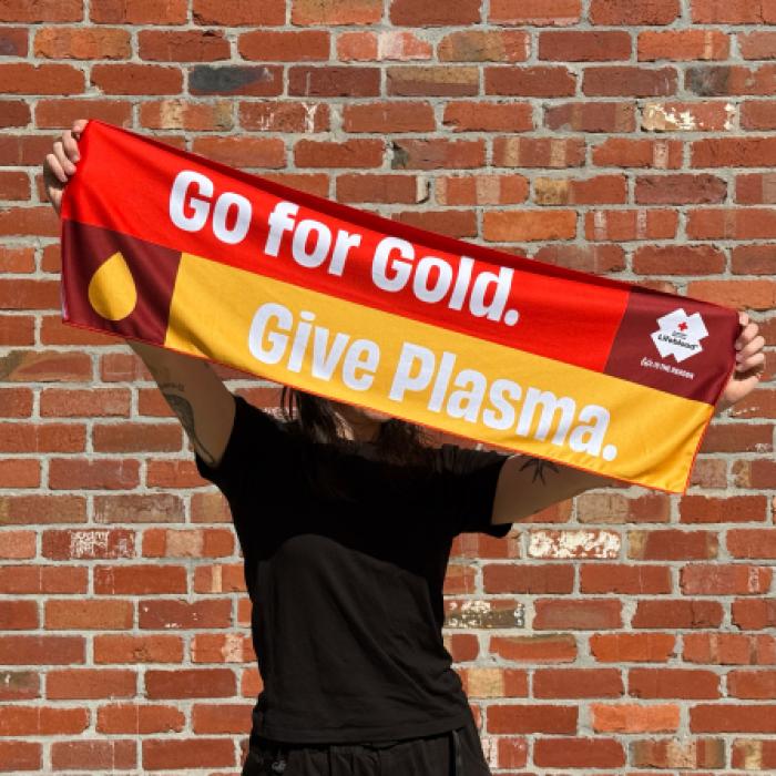 photo of a woman holding up a banner that reads go for gold, give plasma