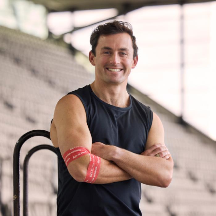 photo of cooper woods wearing a lifeblood bandage around his arm and smiling to camera