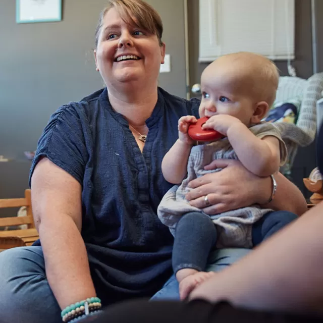 a mother and baby are seated on the floor smiling